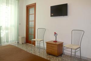 バーリにあるI due Baroni - fronte Campusのテレビ付きの客室で、椅子2脚とドレッサーが備わります。