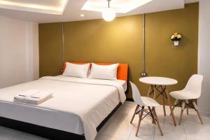 a bedroom with a bed and a table and chairs at The Northeast Hotel in Si Sa Ket