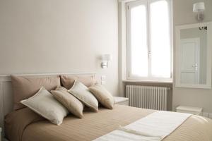 Un dormitorio con una cama con almohadas blancas y una ventana en - Home Sweet Langhe - Room 51, en Alba