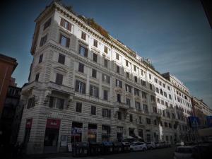 un edificio blanco alto con coches estacionados frente a él en 2 Passi Al Colosseo B&B, en Roma