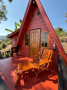 a red cabin with a bench on a deck at Mountain springs resort in Ban Nong Khieo