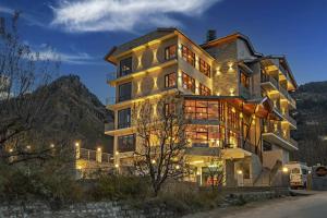 a large building with lights in front of a mountain at Echor Himalayan Aurum Resort & Spa, Manali in Manāli