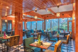 a restaurant with tables and chairs and windows at Echor Himalayan Aurum Resort & Spa, Manali in Manāli +81 photos