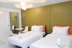 two beds in a room with green walls at The Northeast Hotel in Si Sa Ket +16 photos