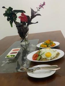 two plates of food on a table with a vase with flowers at Skyline & bitcoin coffee lodge in Kalutara
