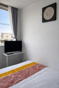 a bedroom with a bed and a flat screen tv at Magokoro House 201 in Nishiizu