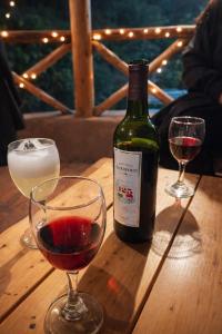 a bottle of wine and two glasses on a wooden table at Apu House in Calca