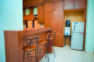 a kitchen with a bar with stools and a refrigerator at Orange Villa in Berastagi