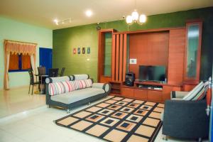 a living room with a couch and a television at Orange Villa in Berastagi