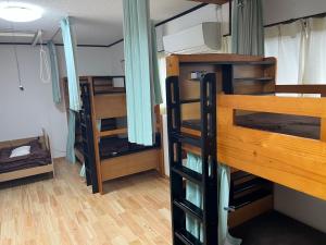 a room with three bunk beds in a room at ゲストハウスまちかど Guest House MACHIKADO in Ibusuki