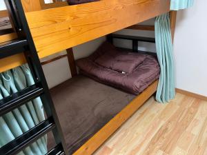 a small bed on the bottom bunk of a bunk bed room at ゲストハウスまちかど Guest House MACHIKADO in Ibusuki