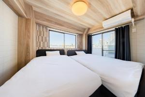 two beds in a room with a window at Matcha Inn Sakura Tokyo in Tokyo