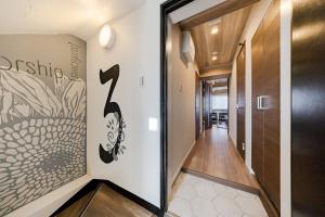 a hallway with a door leading to a hallway with a painting on the wall at Matcha Inn Sakura Tokyo in Tokyo