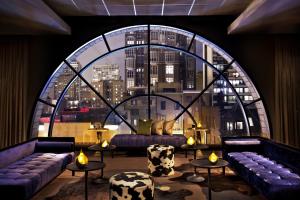 a room with couches and tables and a large window at Thompson Chicago, by Hyatt in Chicago