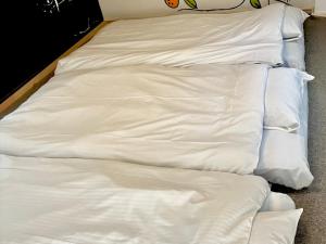 an unmade bed with white sheets on the floor at mkh room TAKAMATSU in Takamatsu