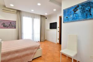 a bedroom with a bed and a chair and a tv at Sa Omu Bianca in Tortolì