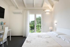 a white bedroom with a bed and a desk and a window at Sa Omu Bianca in Tortolì