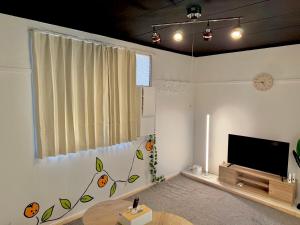 a living room with a flat screen tv and a table at mkh room TAKAMATSU in Takamatsu