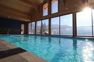 ein großes Schwimmbecken in einem Gebäude mit Fenstern in der Unterkunft Chalet Titlis in Bernex