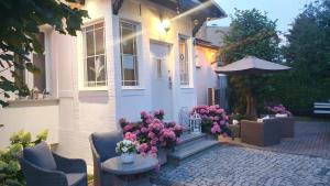 a white house with flowers and an umbrella at Willa Azur blisko plaży, centrum Mielna in Mielno
