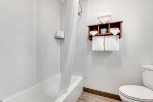 a white bathroom with a toilet and a bath tub at Suburban Studios near Mesa Verde in Cortez