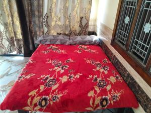 a red comforter on a bed in a room at Shobhit homestay in Amroha