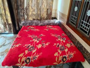 a red comforter on a bed in a room at Shobhit homestay in Amroha