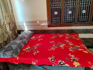 a red blanket on a bed in front of a window at Shobhit homestay in Amroha