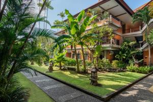 a courtyard with palm trees and a building at Adi Dharma Hotel Kuta in Kuta