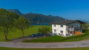 a white house with two cars parked in a field at AlpineHome Apartments Walchsee in Walchsee