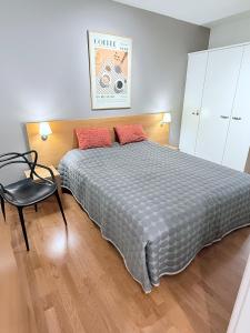a bedroom with a large bed and a chair at Premium Chalet huoneisto kylpylän vieressä in Vierumäki