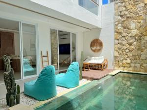 a swimming pool with blue chairs next to a house at Villa Lipa in Ungasan