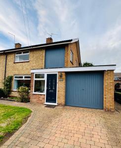 a brick house with a blue garage at Spacious House - Parking - Pool Table in Balderton