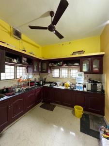 a kitchen with wooden cabinets and a ceiling fan at Hostel Honsa in Cochin