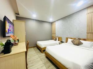 a hotel room with two beds and a television at Hotel Hoài Bảo in Ấp Rạch Mẹo