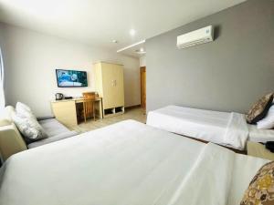 a hotel room with two beds and a desk at Hotel Hoài Bảo in Ấp Rạch Mẹo +1 photo