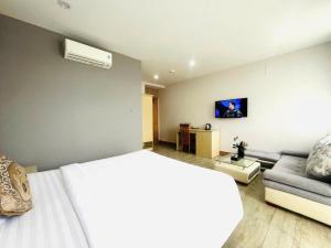a bedroom with a white bed and a couch at Hotel Hoài Bảo in Ấp Rạch Mẹo
