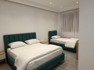 two beds in a room with white and green at Rezidenca Pahumi 2 in Durrës