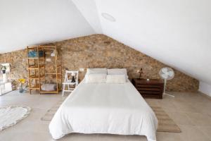 a bedroom with a white bed and a stone wall at O Cabanel in Fisterra