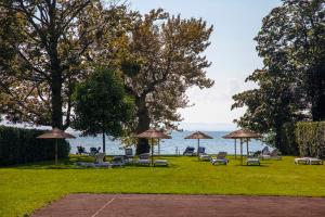 a park with chairs and umbrellas and the water at Sonnenhof Apartments in Kressbronn am Bodensee