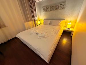 a bedroom with a white bed with two towels on it at Sibiutiful - Ultracentral in Sibiu