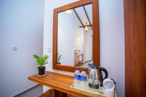 a mirror on a wooden table with water bottles on it at The Clouds Ahangama in Ahangama