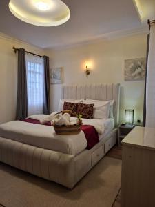 a bedroom with a large white bed with a basket on it at Pearl Apartment Ruaka in Ruaka