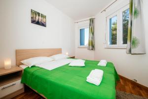 zielone łóżko w białym pokoju z oknami w obiekcie Rainbow apartments w mieście Zadar