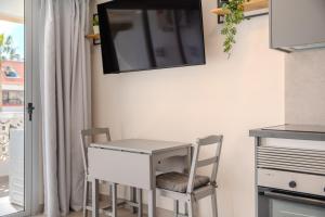 a desk with two chairs and a tv on the wall at Playa Honda Design, Comfort & Pool in Playa de las Americas