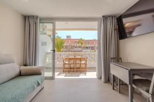 a living room with a couch and a desk and a balcony at Playa Honda Design, Comfort & Pool in Playa de las Americas