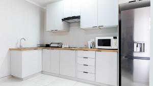 a kitchen with white cabinets and a stainless steel refrigerator at Deluxe on Main in Roodepoort +2 photos