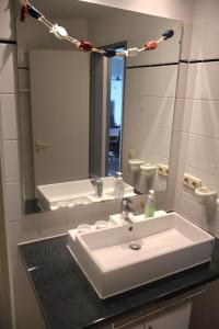a bathroom with a white sink and a mirror at Ferienwohnung Ortlieb Laboe in Laboe +11 photos