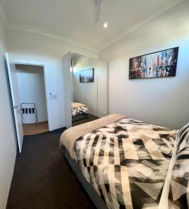 a bedroom with a bed with a checkered blanket at il Villinno on Dalton - Great Location in Mosman Park