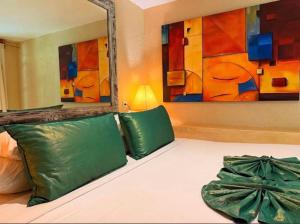 a bed with two green pillows and a mirror at Villa dengan pemandangan kolam renang in Canggu
